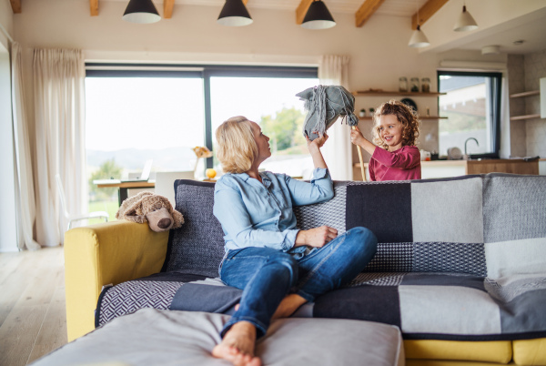 A happy cute small girl with mother indoors at home, playing.