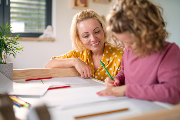 A cute small girl with mother in bedroom indoors at home, drawing pictures.