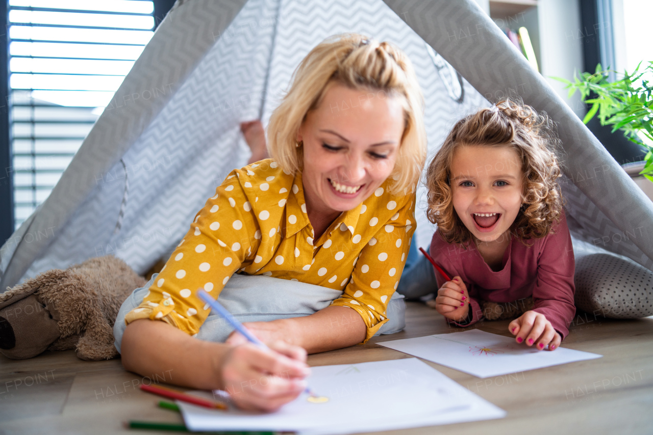 A cute small girl with mother in bedroom indoors at home, drawing pictures.