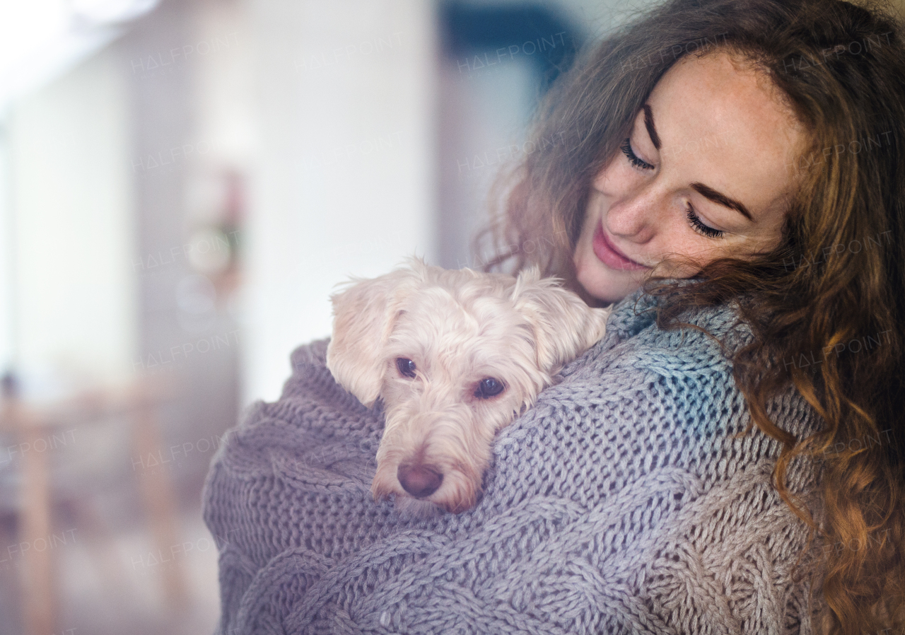 Young woman relaxing indoors at home with pet dog. Shot through glass.