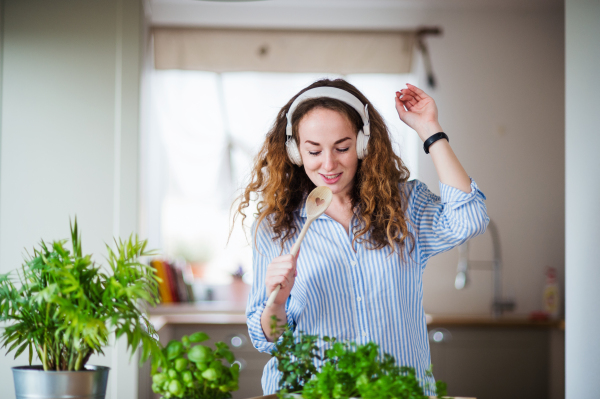 Young woman with headphones relaxing indoors at home, listening to music and singing.