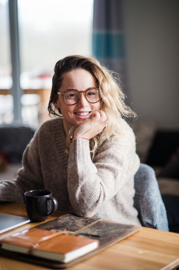 Portrait of young woman or student studying indoors at home, looking at camera.