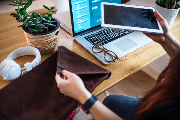 Midsection of senior woman with tablet and laptop working in home office.