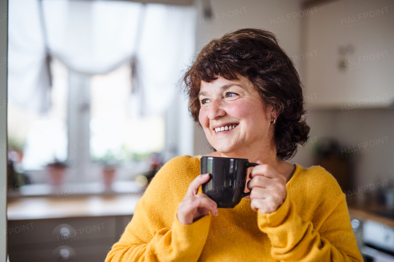 Portrait of senior woman with cup of coffee at home, relaxing.