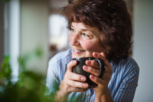 Portrait of senior woman with cup of coffee at home, relaxing.