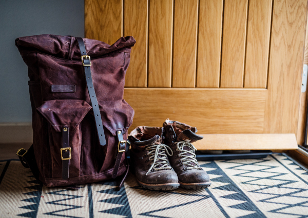 Pair of boots and backpack by open front door. Copy space.