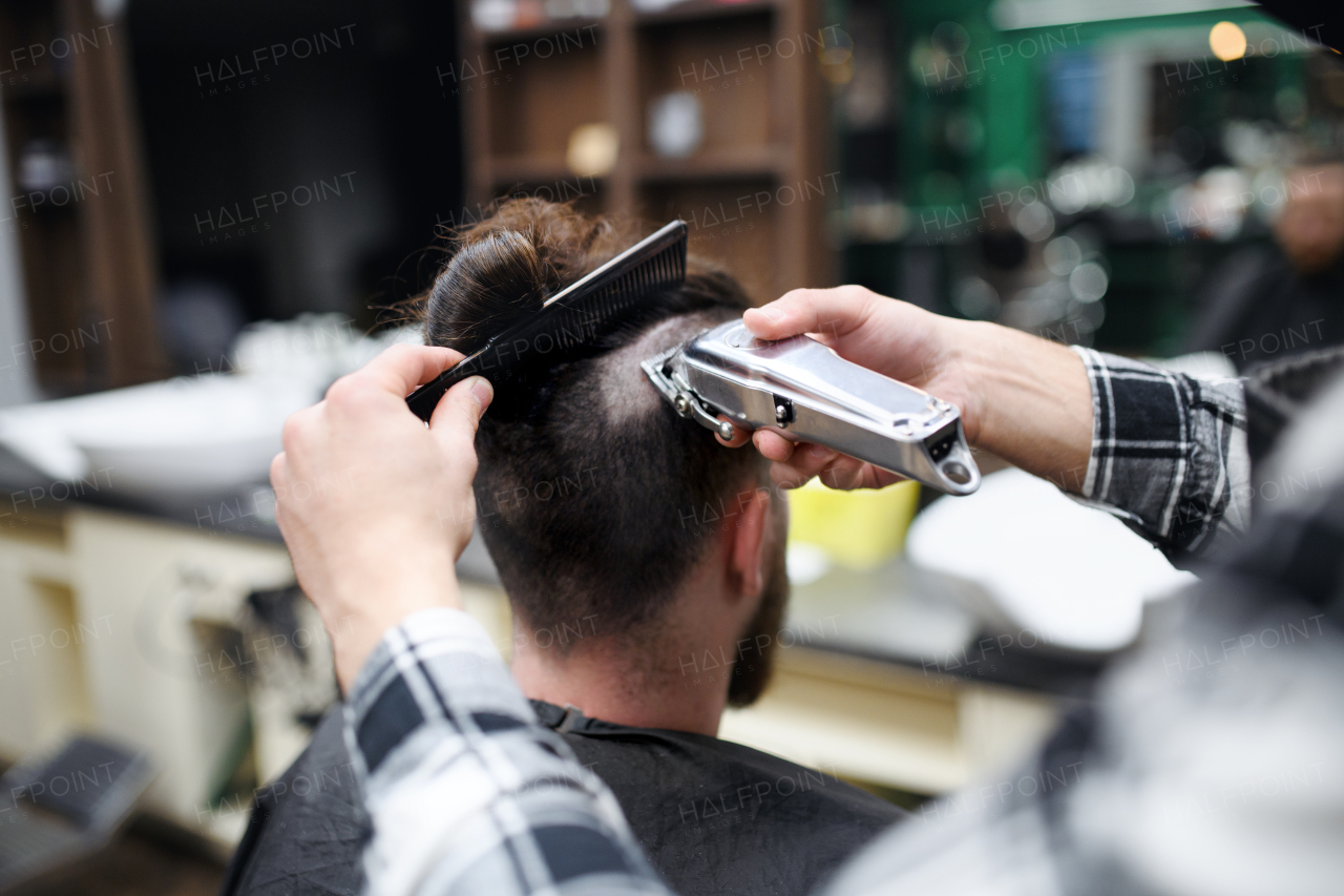 A rear view of man client visiting haidresser in barber shop.