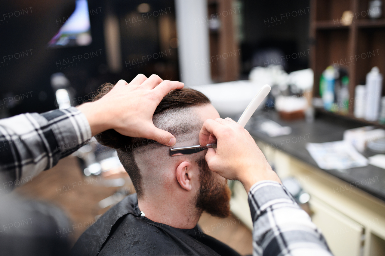 A rear view of man client visiting haidresser in barber shop.