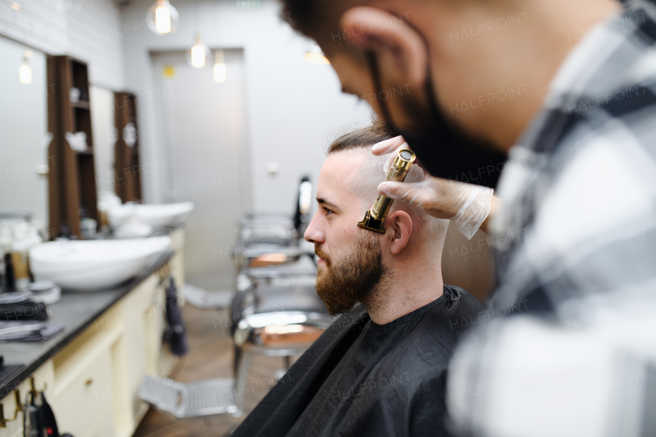 Man client visiting haidresser and hairstylist in barber shop, coronavirus and new normal concept.