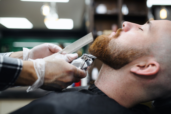 A young man client visiting haidresser in barber shop, midsection and close-up.