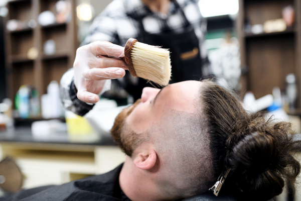 Man client visiting haidresser and hairstylist in barber shop, coronavirus and new normal concept.