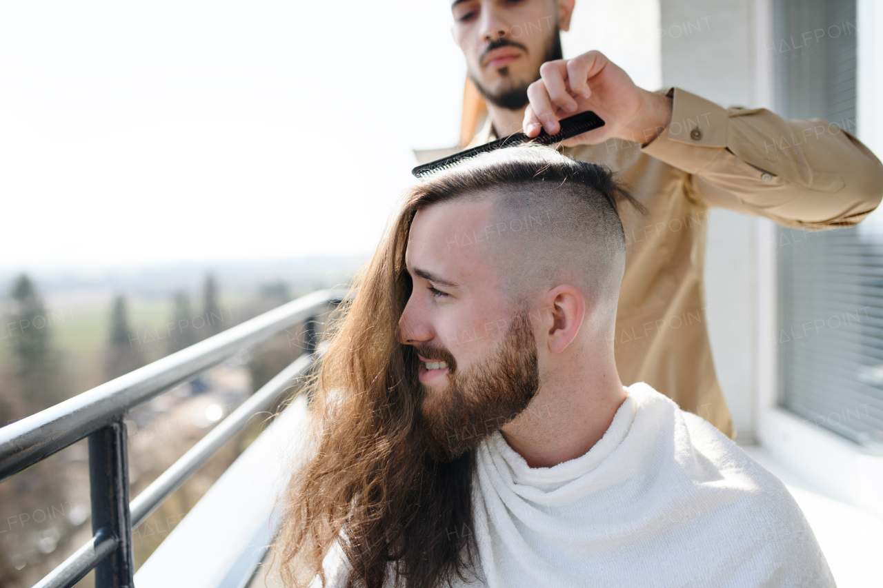 Haircut on a balcony at home, coronavirus and lockdown concept.