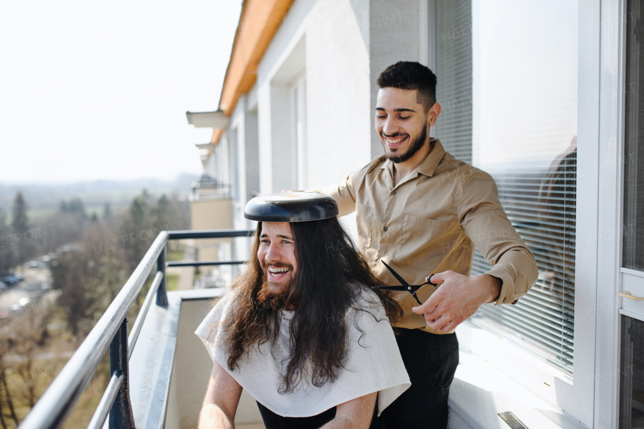 A haircut on balcony at home, coronavirus, lockdown, friendship and fun concept.