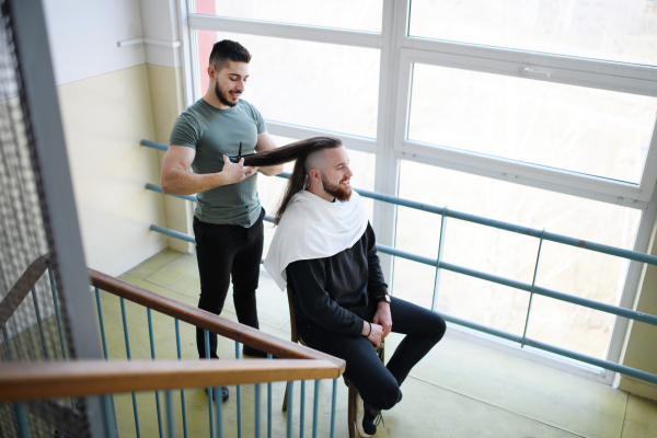 Haircut in a corridor in block of flats at home, coronavirus and lockdown concept.