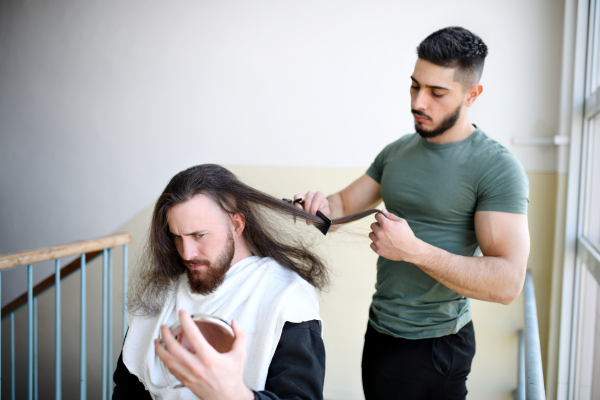 Haircut in a corridor in block of flats at home, coronavirus and lockdown concept.