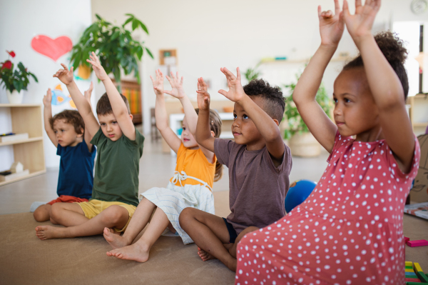 A group of small nursery school children sitting on floor indoors in classroom, playing.