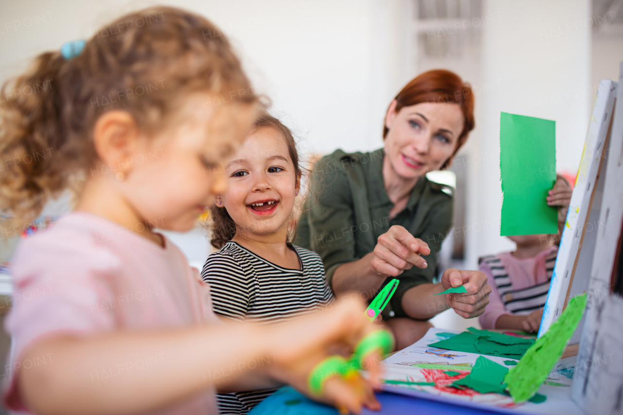 A group of small nursery school children with teacher indoors in classroom, art and craft concept.