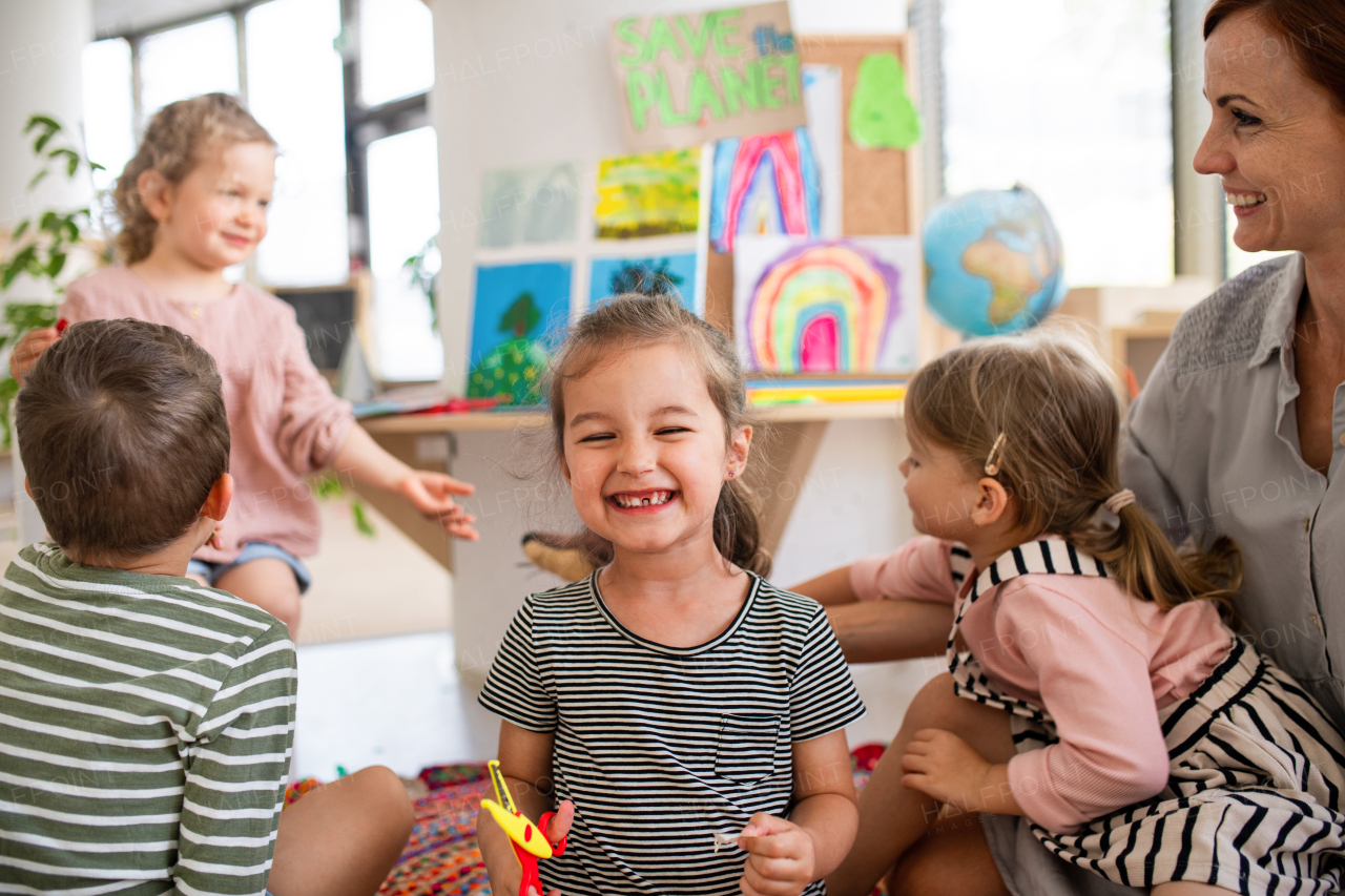 Happy small girl showing lost baby tooth indoors in classroom, looking at camera.