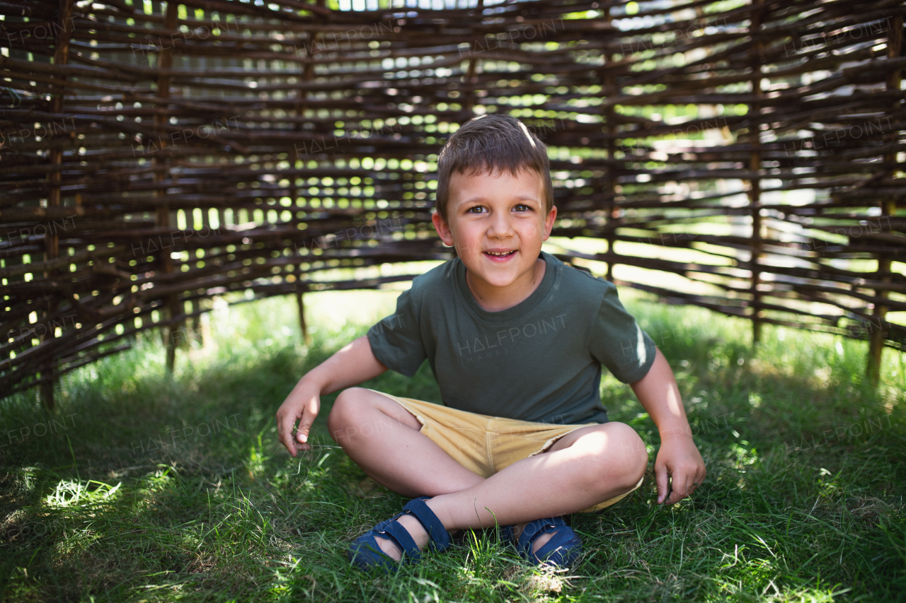 A small nursery school boy playing outdoors on playground, looking at camera