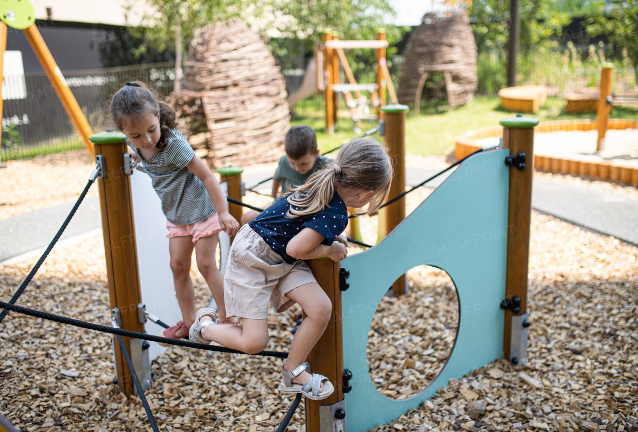 A group of small nursery school children playing outdoors on playground.