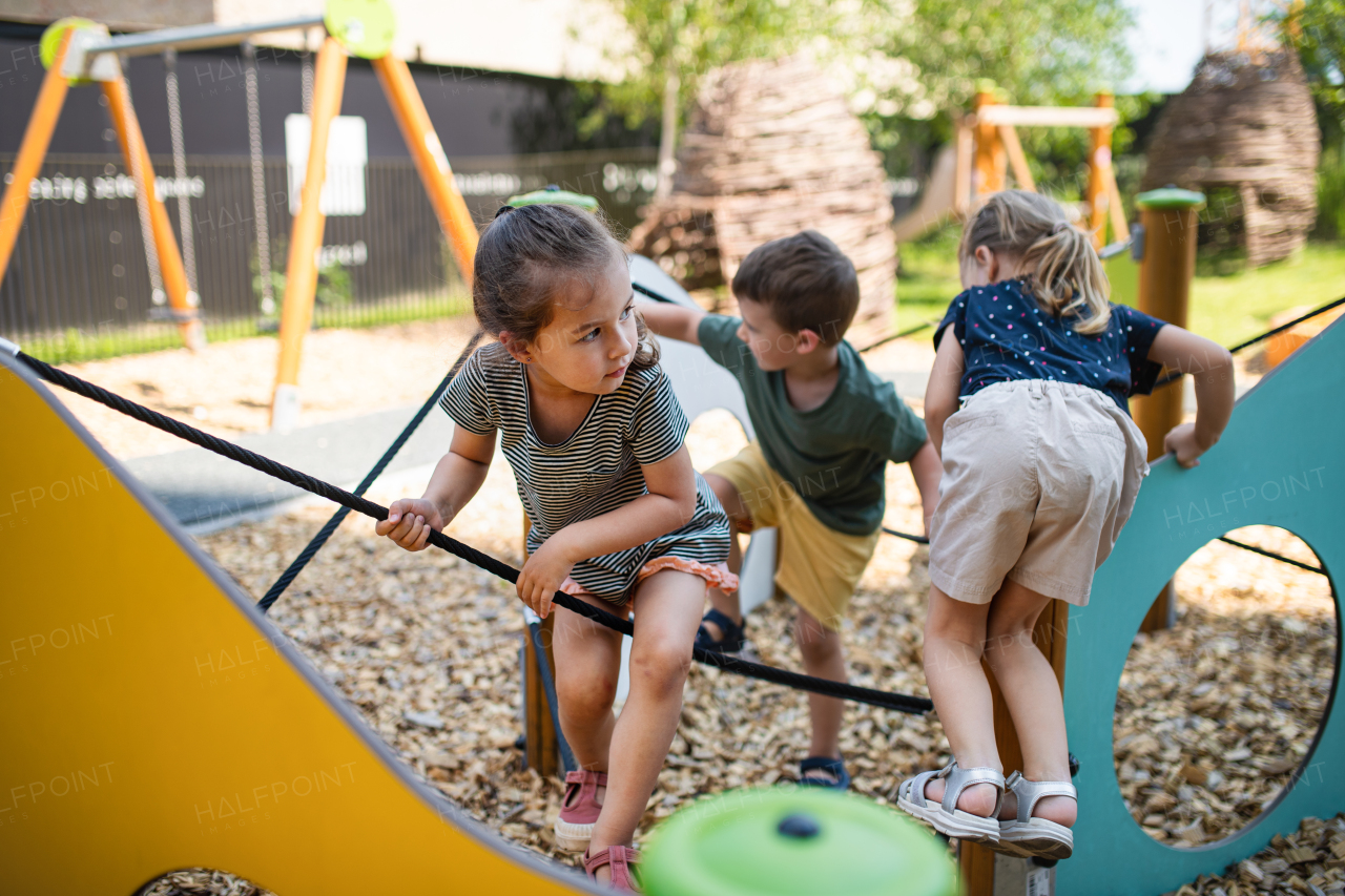 A group of small nursery school children playing outdoors on playground.