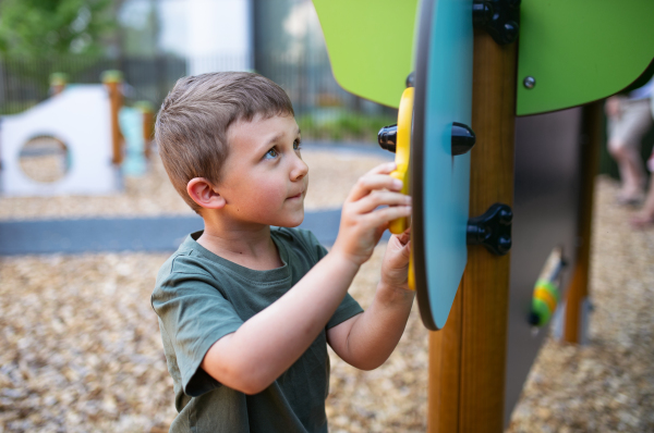 A small happy nursery school boy playing outdoors on playground.