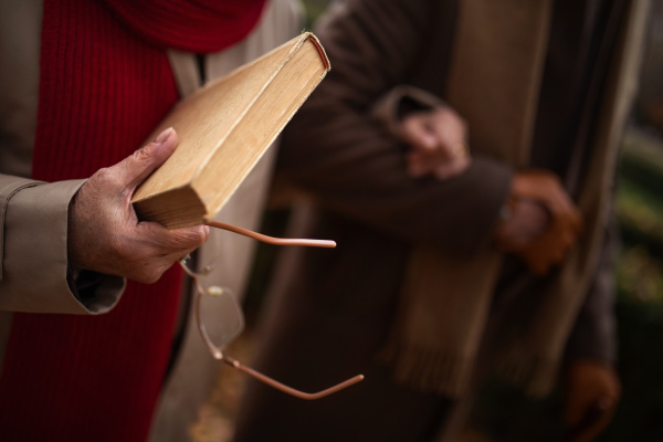 Close-up of senior couple holding a book and glasses during autumn walk.