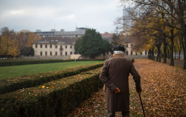 An old elegant man with walking stick on walk in park on autumn day