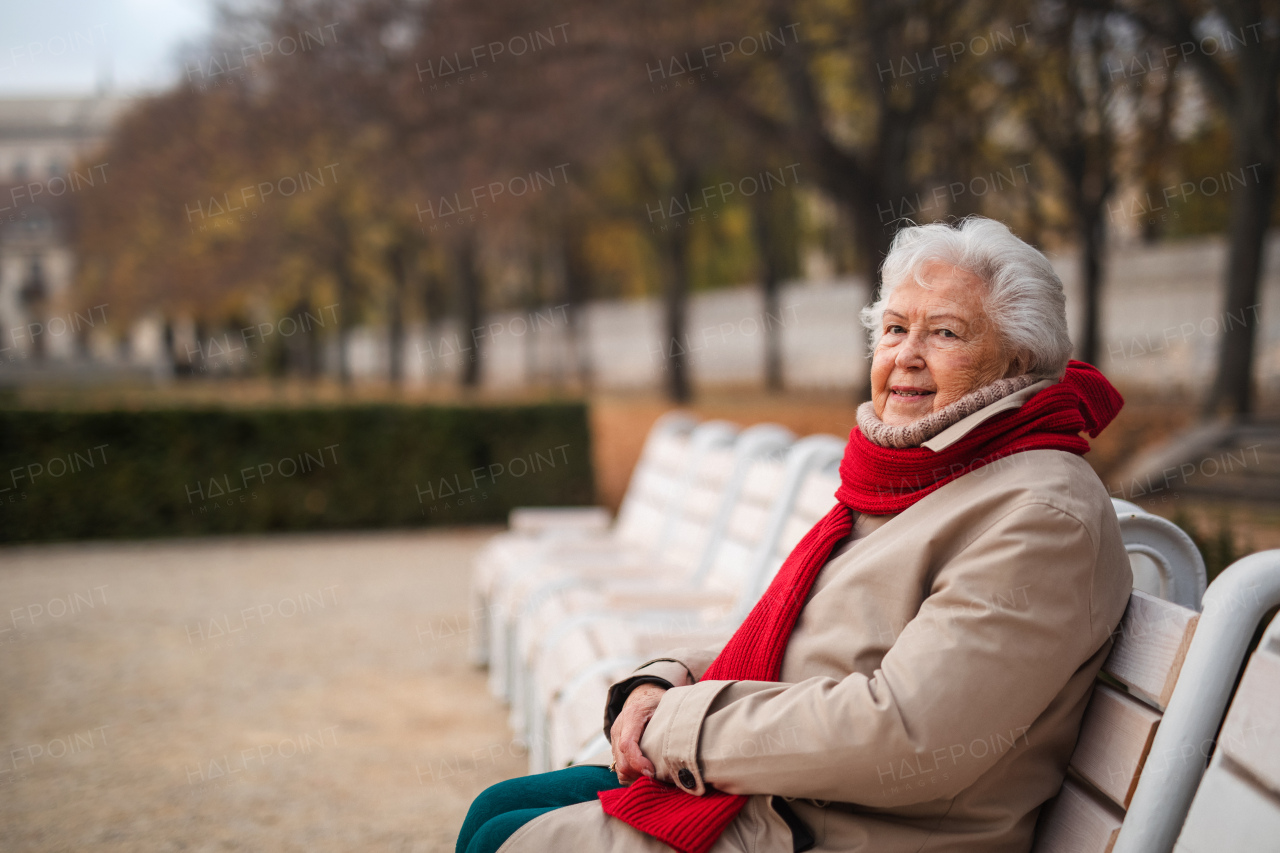 A senior woman sitting on bench in town park in autumn, resting