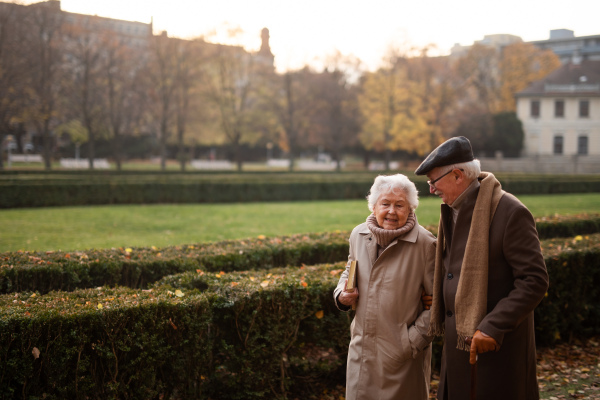 senior friends on walk outdoors in a park on autumn day, copy space.