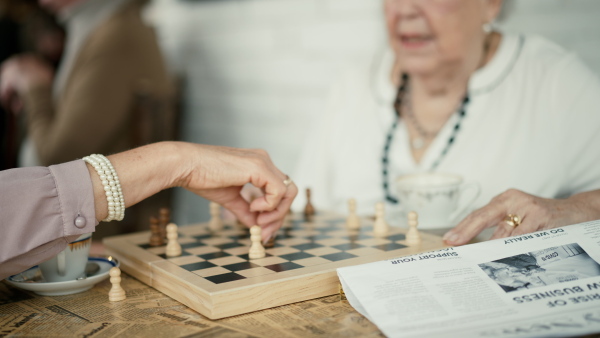 Senior friends enjoying time together and playing chess indoors in a cafe.