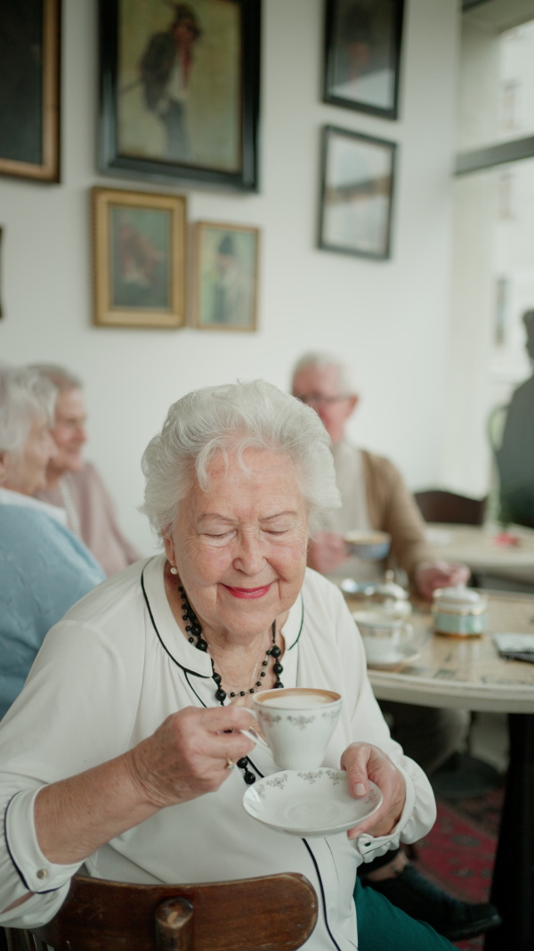 Happy senior woman drinking coffee in a cafe, smiling and looking at camera.