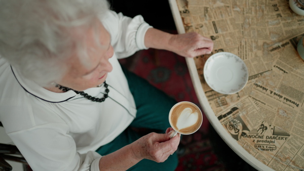 Top view of elderly woman having a nostalgic moment while drinking a hot drink from cup.