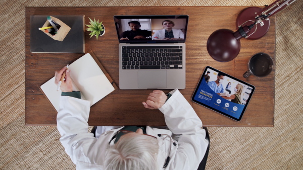 A top view of senior doctor having an online consultation on laptop. Lockdown concept.