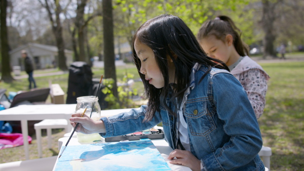 A small children having art class outdoors in city park, learning group education concept.