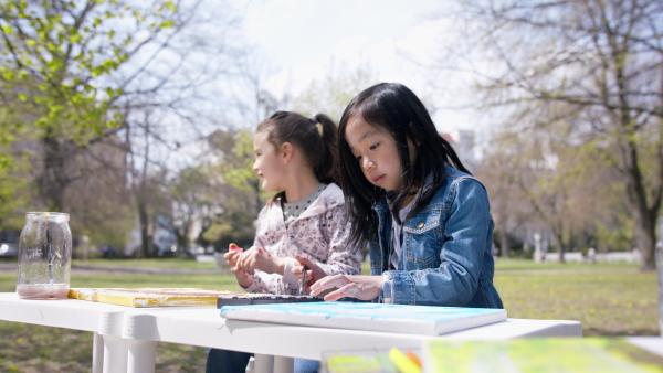 A small children having art class outdoors in city park, learning group education concept.