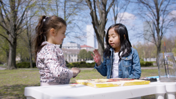 A small children having art class outdoors in city park, learning group education concept.