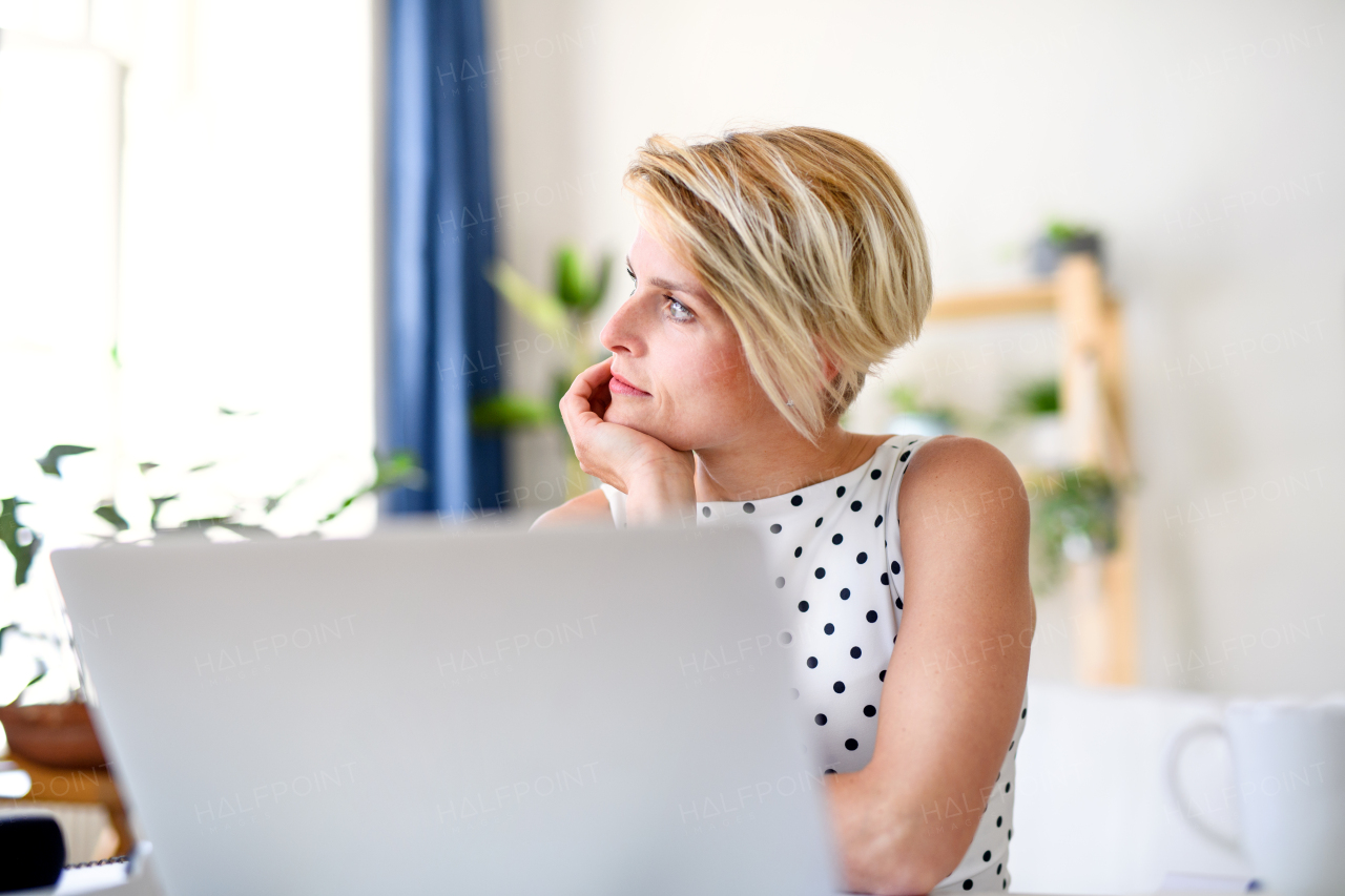 Sad and tired young businesswoman with laptop indoors in home office, working.