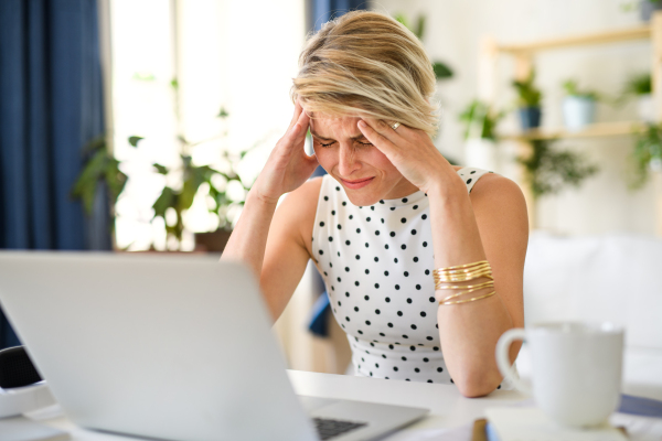 Frustrated and disappointed young businesswoman with laptop indoors in home office, working.