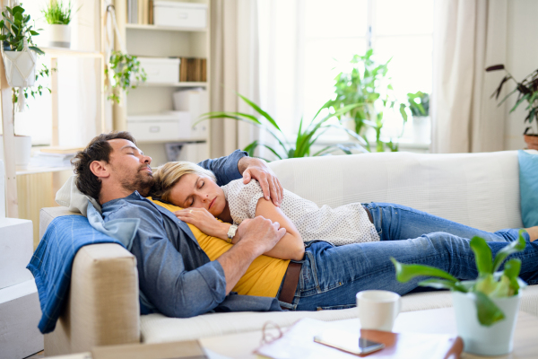 Happy couple in love lying on sofa indoors at home, sleeping.