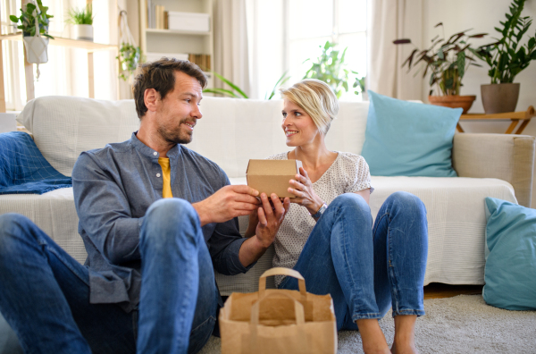 Front view of happy couple sitting on floor indoors at home, fast food delivery concept.