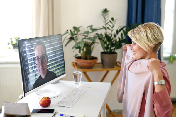 Young woman having video call on computer at home, friend giving fashion advice.