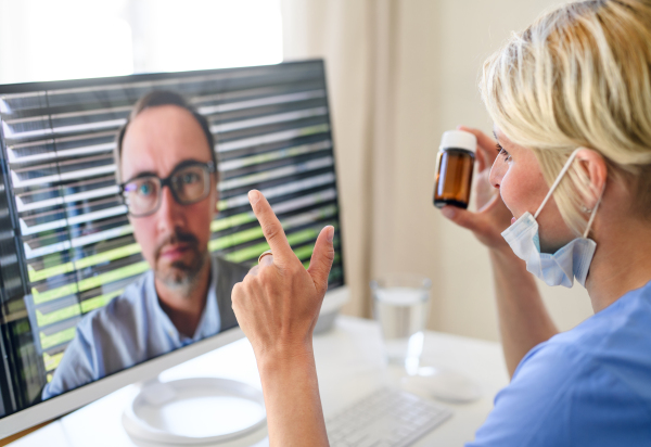 Side view of woman doctor having video call with patient on laptop, online consultation concept.