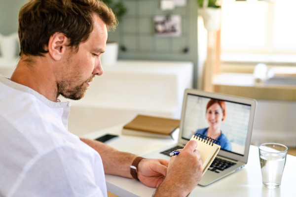 Mature man having video call with doctor on laptop at home, online consultation concept.