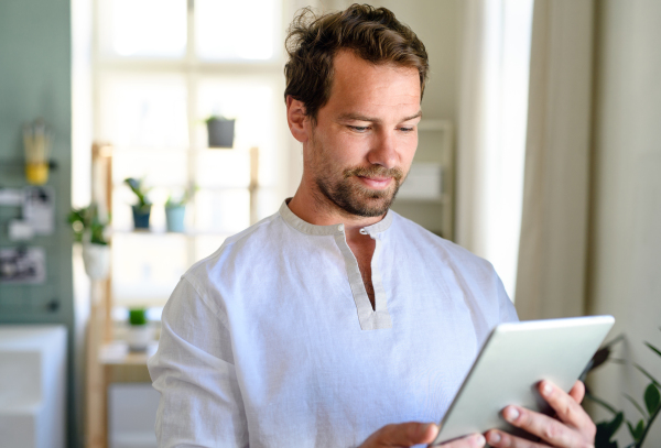 Front view wais-up portrait of man using tablet at home.