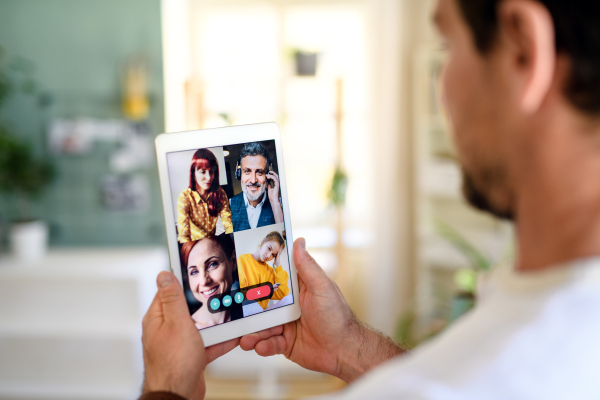 Midsection of unrecognizable man having video call on tablet at home.