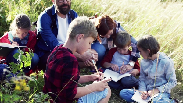 A group of small school children with teacher on field trip in nature. Slow motion.