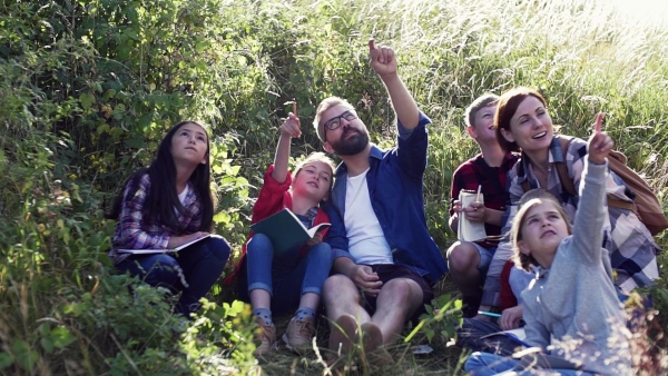 A group of small school children with teacher on field trip in nature. Slow motion.