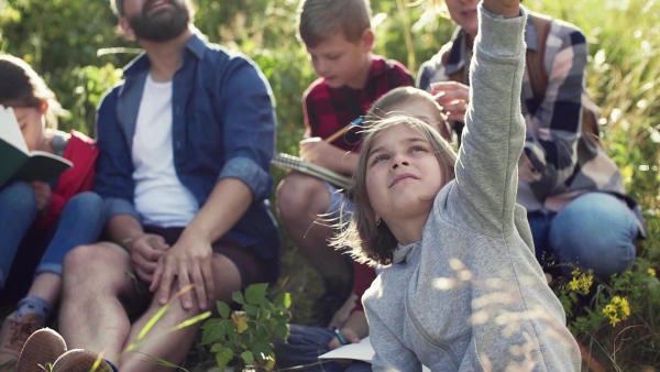 A group of small school children with teacher on field trip in nature. Slow motion.