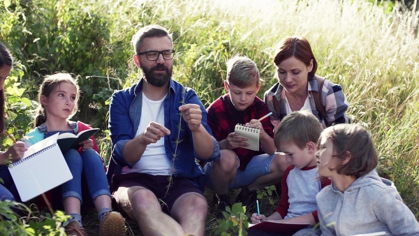 A group of small school children with teacher on field trip in nature. Slow motion.